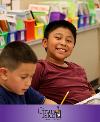  Smiling Howard Elementary student sitting at desk with pencil and crayons. 